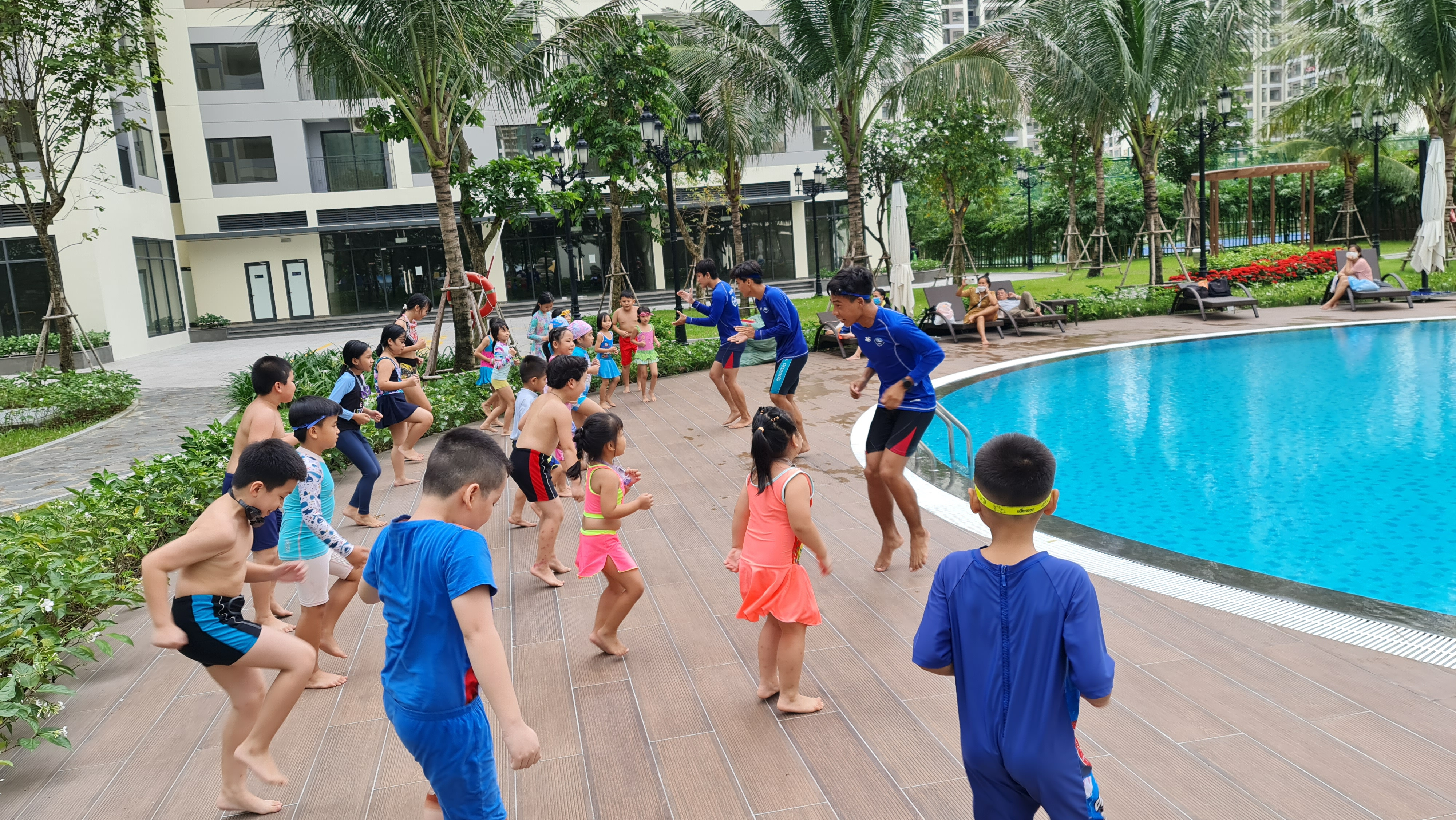 Học viên và huấn luyện viên thực hiện khởi động giãn cơ làm nóng cơ thể bên thành bể bơi